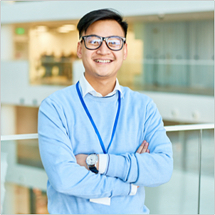 A smartly dressed man crossing his arms and smiling at the camera 