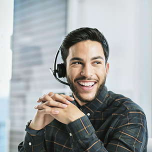 A man wearing a headset and laughing while looking off to the side