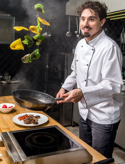 A chef flipping vegetables in a frying pan