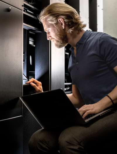 Technician working on a server rack and his laptop 