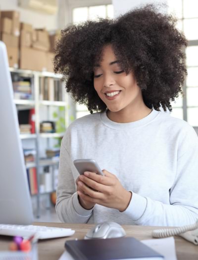 Woman looking at her smartphone at a standing desk whilst using Microsoft Office 365