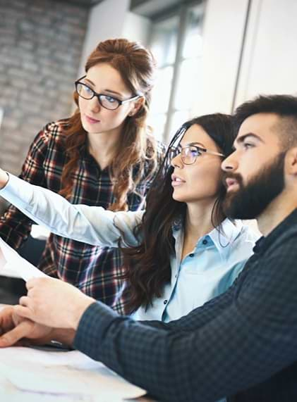 Three people looking at a monitor, comparing options as part of the website design service